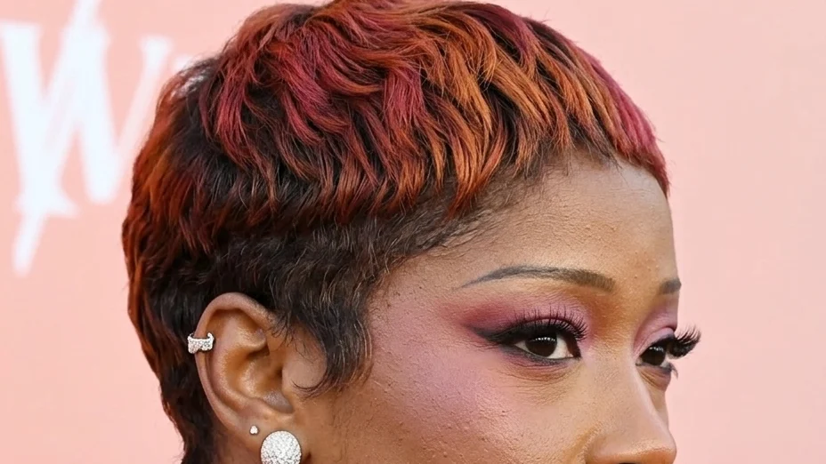 Keke Palmer appears at an event in a red and dark pink pixie cut and pink eyeshadow.