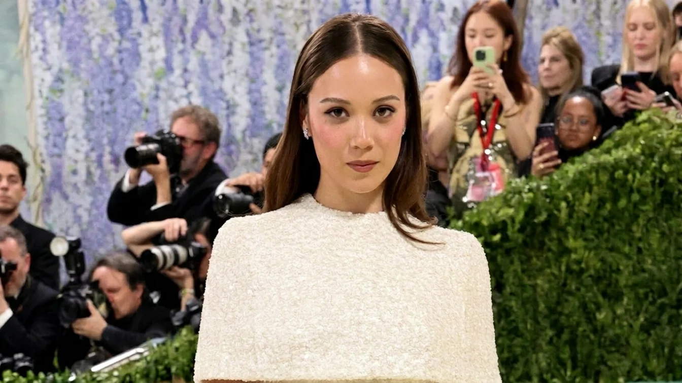 Laufey wears an ivory capelet dress and soft waves.