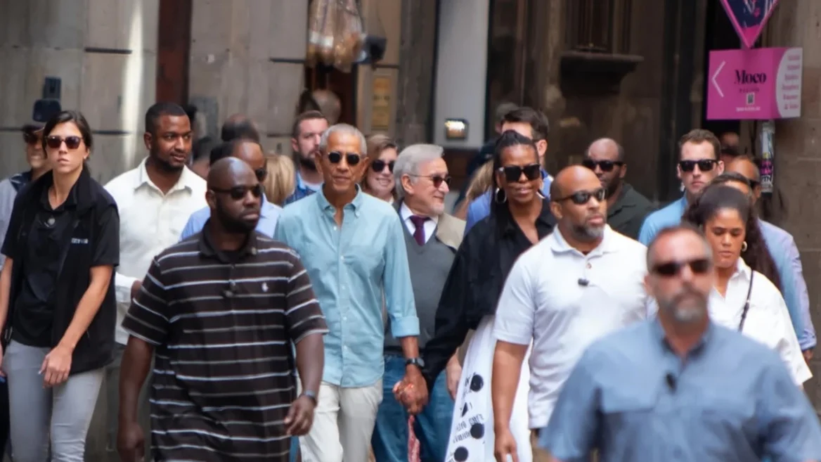 Barack Obama (C,L), his wife Michelle (C,R) and US director Steven Spielberg (C) walk in a street of Barcelona on April 28, 2023