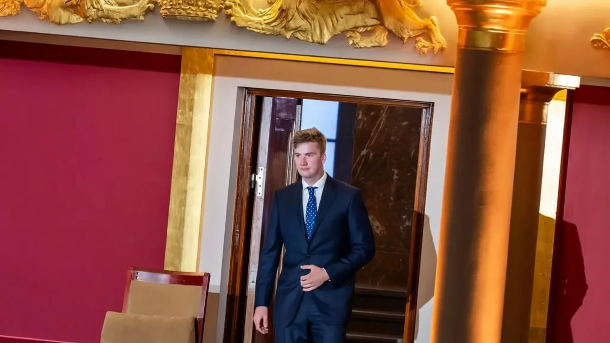 Prince Gabriel in a blue suit heading to a chair
