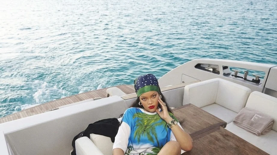 Rihanna puts her feet up on a boat in PUMA Cat Cleat Jelly sandals during her FENTY x PUMA launch celebration in Barbados on March 13