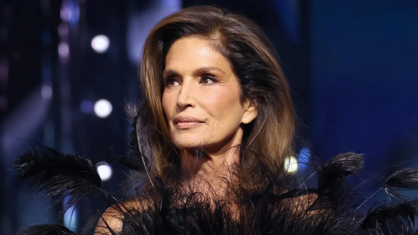 Cindy Crawford walking in a Gucci fashion show in a black feathered dress