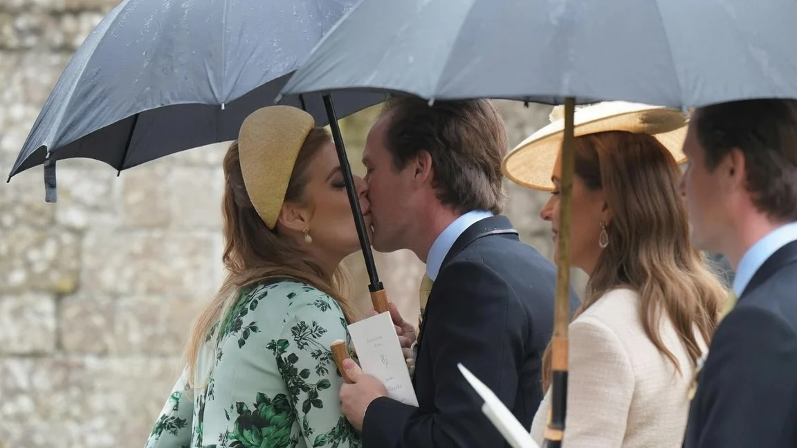 Prince William kissing Princess Beatrice on the cheek underneath an umbrella