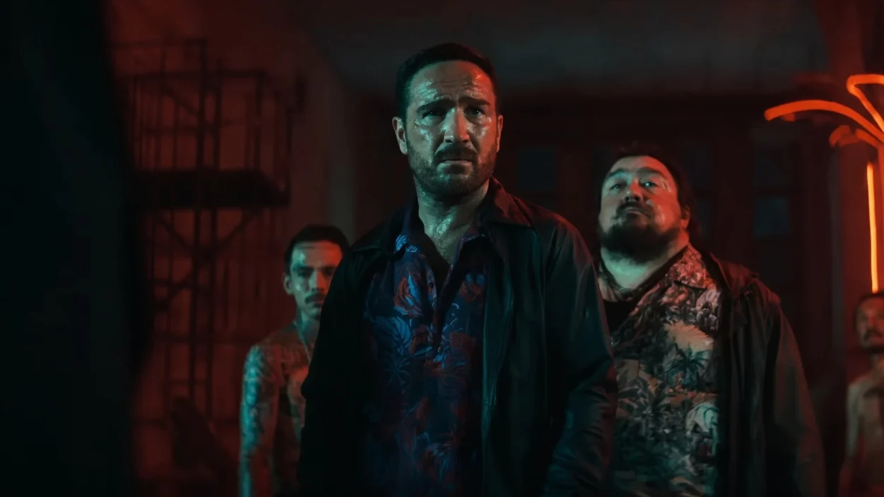 Frederick Lau and three other men stand in a dimly lit room with red lighting.